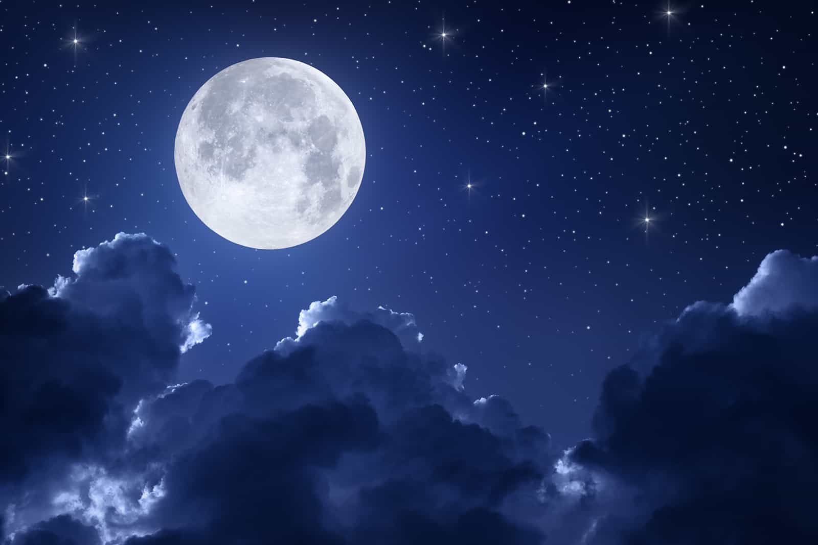 Bright full moon, clouds, and stars in a dark blue night sky.
