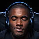 Man with closed eyes wearing over-ear headphones on a dark background.