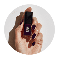 Hand with freshly painted nails holding up a bottle of JINsoon black nail polish.